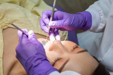 Dişçinin diş bakımı yaparken ve diş kontrolü yaparken fotoğrafını çek. Klinikteki genç Asyalı kadına götür. Sağlık ve diş sağlığı kavramı