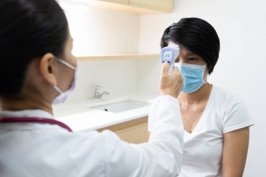 Hasta bir kadının ısısını ölçmek için dijital termometre kullanan bir hemşire. covid-19, coronavirüs, tıbbi, sağlık, ateş konsepti