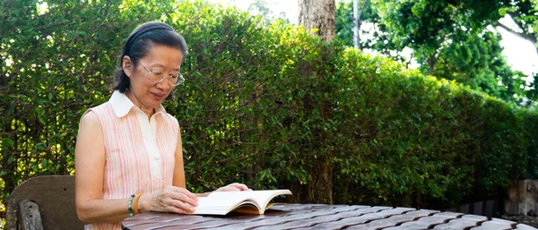 Banner Picture Senior Asian Woman Wearing Eyeglasses Sitting Garden Reading — Stock Photo, Image