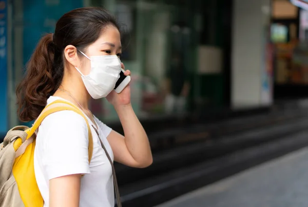 Νεαρή Ασιάτισσα Που Φορούσε Μάσκα Προσώπου Χρησιμοποιώντας Smartphone Και Περπατούσε — Φωτογραφία Αρχείου
