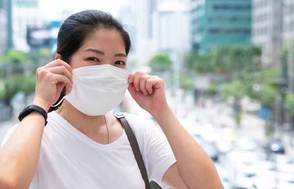 スマートフォンを使って顔のマスクをしたアジア系の若い女性が街を歩いているのは コロナウイルスの流行やコロナウイルス感染時です 社会的距離と新しい通常のライフスタイルコンセプト — ストック写真