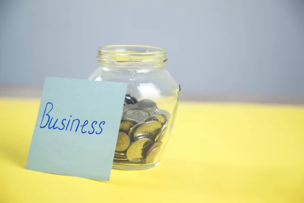 business text on paper with coins on jar
