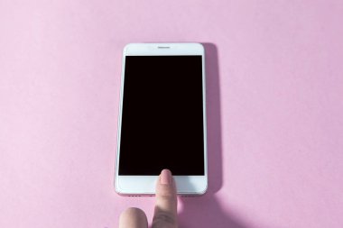 Kadın masadaki akıllı telefona dokunuyor.