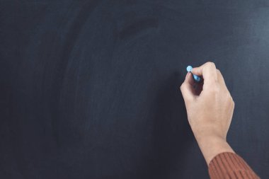 Kadın tebeşirle yazı tahtasında el ele tutuşuyor.