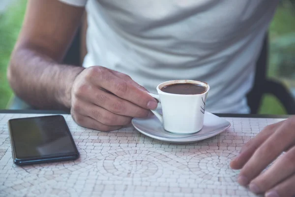 man hand coffee with phone in cafe