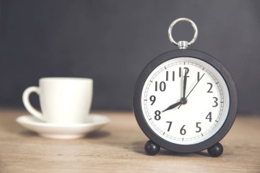 Masasında bir fincan kahve olan saat.