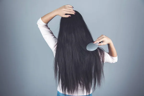 Frau Kämmen Haare Auf Der Grauen Wand Hintergrund — Stockfoto