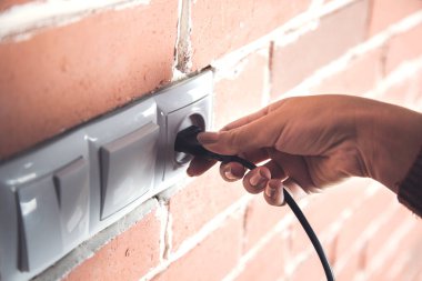 Adam evdeki güç kablosunu takıyor.