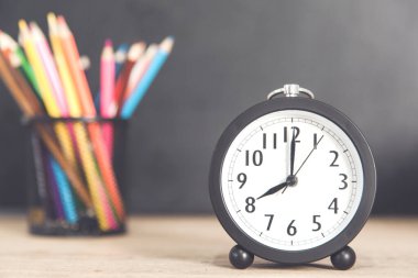 Masasında renkli kalemler olan bir saat.