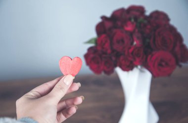 Kadın eli kırmızı, masasında güller var.