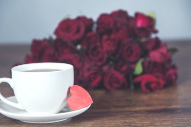 Masada kahve ve kalp dolu kırmızı güller.