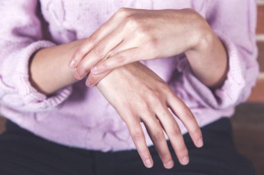 Genç bir kadın arka planda el ele acı çekiyor.