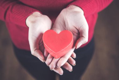 Kırmızı kalbi tutan genç bir kadın. 