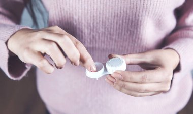 Genç kadın lensleri tutuyor.