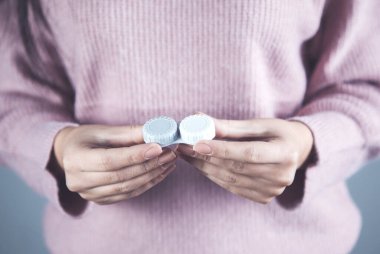 Genç kadın lensleri tutuyor.