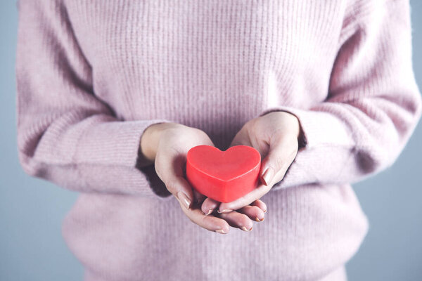woman holding red heart on gray background