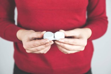 Gri arka planda kadın lensleri tutuyor