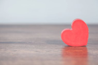 Ahşap masa arkasında kırmızı kalp.