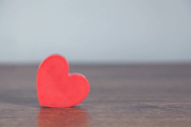 Ahşap masa arkasında kırmızı kalp.