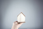 nő kéz gazdaság fa ház modell szürke háttér
