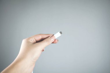Gri arka planda telefon şarj aleti tutan kadın.
