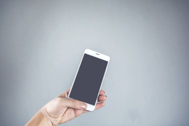 Gri arka planda akıllı telefonu tutan kadın.