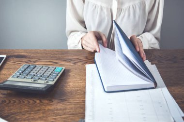İş kadını büro masasında not defteri tutuyor.