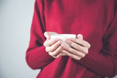 Bir fincan kahve ya da çay tutan bir kadın.