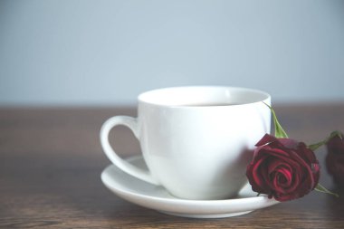 Masanın üzerinde kırmızı gül ve kahve var.
