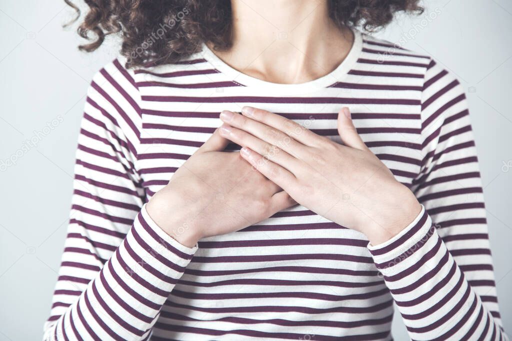 woman hand on heart on the gray background