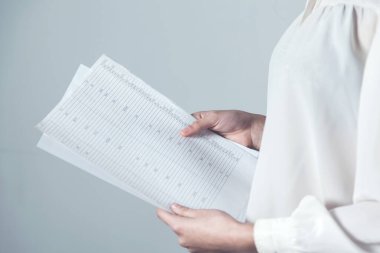 Kadınlar el ele tutuştukları belgeleri gri arka planda tutuyor