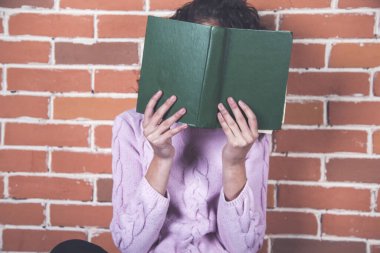 Kadın el kitabı tuğla duvarın arkasında.