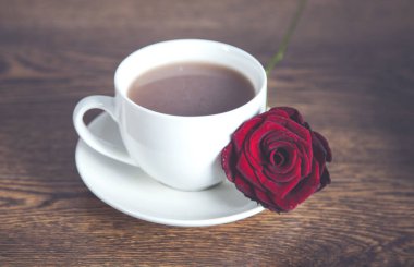 Masanın üzerinde kırmızı güller ve bir fincan kahve