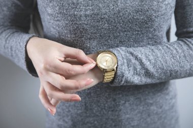 Gri arka planda genç kadın el saati