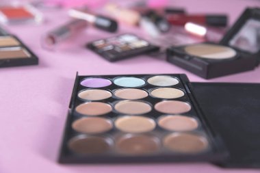 Pembe arka planda farklı makyaj ürünleri