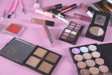 Pembe arka planda farklı makyaj ürünleri