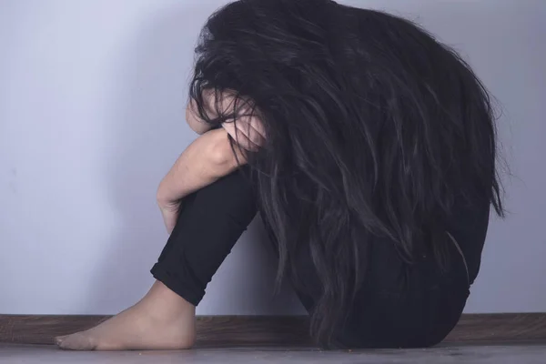 Traurige Frau Sitzt Auf Dem Boden Vor Grauem Hintergrund — Stockfoto