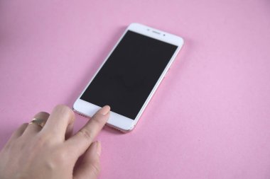 Genç bir kadın elinde beyaz akıllı telefon tutuyor.