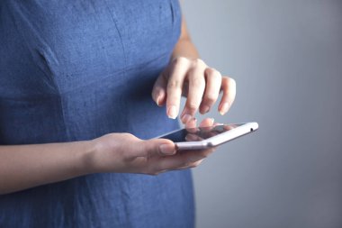 Gri arka planda bir kadın el akıllı telefonu