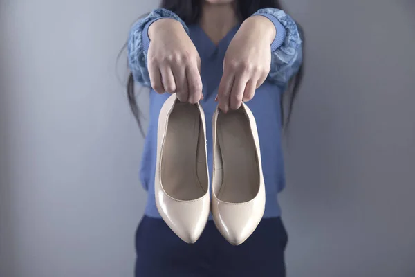 Mano Mujer Sosteniendo Zapatos Blancos Sobre Fondo Gris —  Fotos de Stock