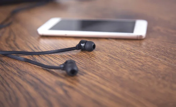 Earphone and smart phone on the table background