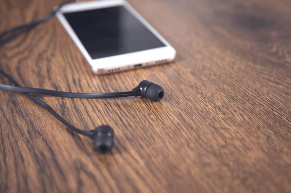 Earphone and smart phone on the table background