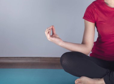 Meditasyon yapan kadın halıda oturuyor.