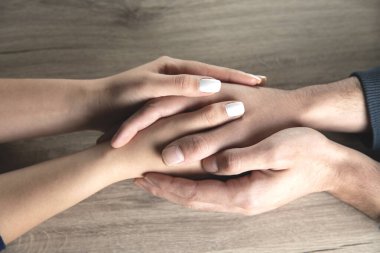 Kadın ve erkek elleri masanın arkasında.