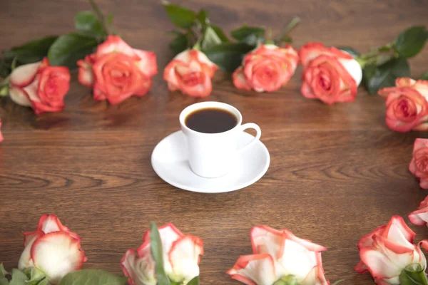 Masada güller olan bir fincan kahve.