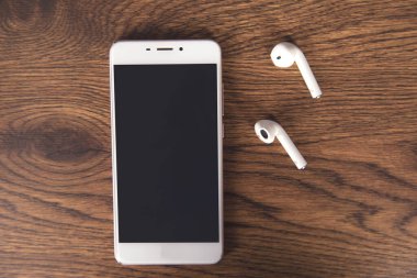 Kulaklık ve telefon ahşap masada.