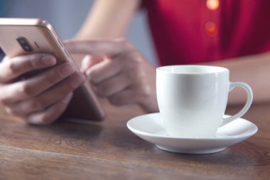 Kadın eli kahve ve akıllı telefon.