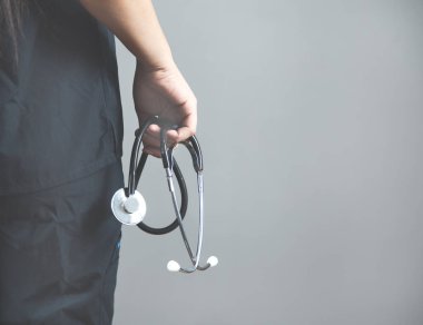 Kadın doktor, gri arka planda steteskop var.