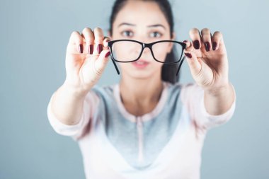 Gri arka planda gözlüklü kadın.