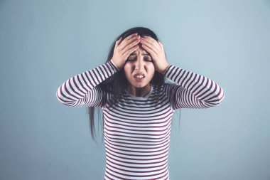 Gri arka planda başı ağrıyan bir kadın